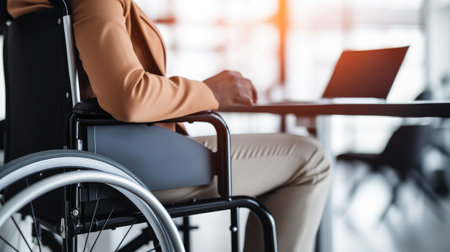strength of diversity with a woman in a wheelchair at an office desk. Unrecognizable hand close-up. Ideal for promoting workplace equality and accessibility.の素材