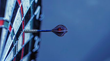 A dart finds the bullseye on a vibrant dartboard against a serene blue sky, symbolizing success and precision. Invest in hitting your goals.の素材