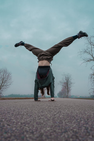 A girl is doing a handstand or cartwheel. A young girl doing sports and her legs stretched out in...