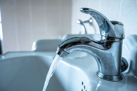 A running tap with the water running. The tap lets the water run with no one in the picture.の写真素材