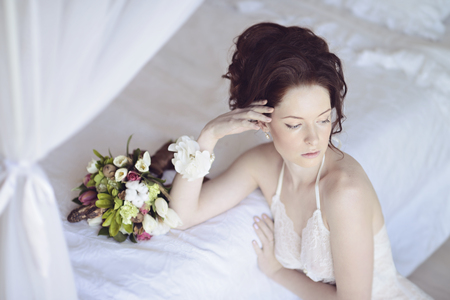 Beautiful sexy lady in elegant white panties and bra. Fashion portrait of model with bouquet indoors. Beauty brunette woman with attractive body in lace lingerie. Female ass in underwear. Naked girlの写真素材