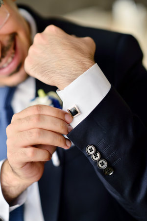 Groom is wearing cuff-links indoors.