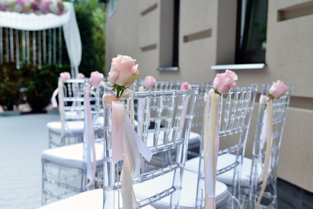Beautiful wedding arch and chairs for marriage decorated with lace fabric and flowers. White decor for bride and groom. Colorful decoration for celebration. Beauty bridal interiorの写真素材