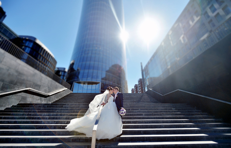 Wedding couple on the nature is hugging each other. Beautiful model girl in white dress. Man in suit. Beauty bride with groom. Female and male portrait. Woman with lace veil. Lady and guy outdoorsの写真素材