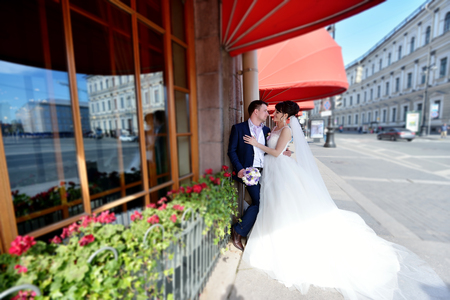 Wedding couple on the nature is hugging each other. Beautiful model girl in white dress. Man in suit. Beauty bride with groom. Female and male portrait. Woman with lace veil. Lady and guy outdoorsの写真素材