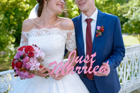 Wedding couple on the nature is hugging each other. Beautiful model girl in white dress. Man in suit. Beauty bride with groom. Female and male portrait. Woman with lace veil. Lady and guy outdoorsの写真素材