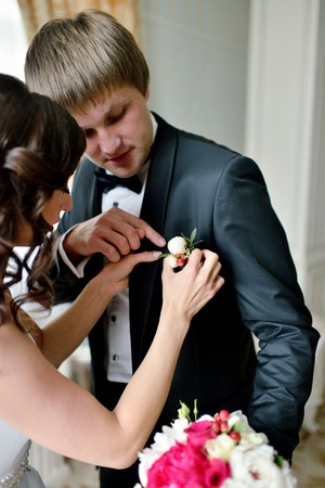 Groom and bride are wearing a boutonniere indoorsの写真素材