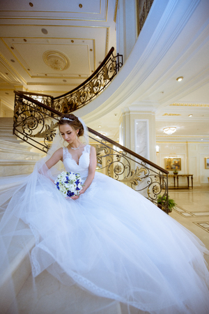 Beauty bride in bridal gown with bouquet and lace veil indoorsの写真素材