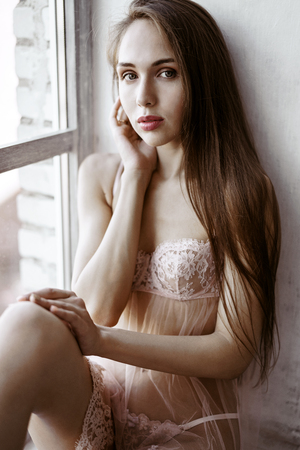 Fashionable female portrait of cute lady in pink robe and panties indoorsの写真素材