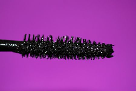 A close-up of the bristles of a mascara wand, with black make-up and a purple background.の写真素材