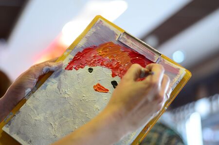 artist paints a picture of oil paint brush in hand with palette closeupの写真素材