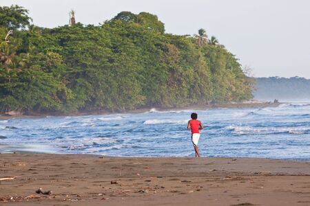 Man running in the surf on the tropical beachの写真素材