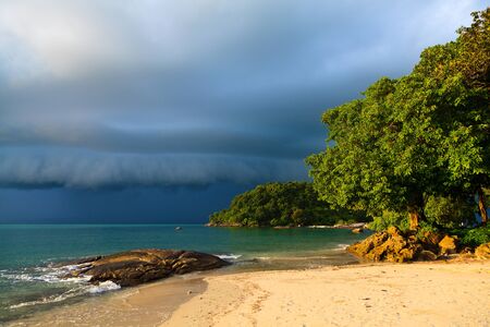 Thunder storm approaching the tropical beach lit by sunの写真素材