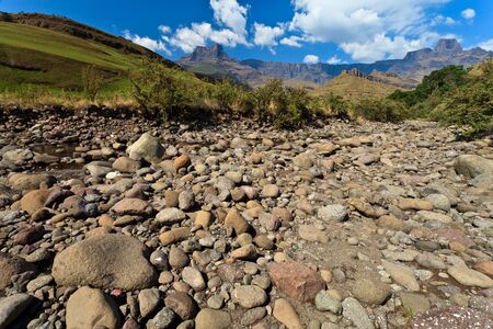 Dry riverbed with mountains in the background on a sunny dayの写真素材