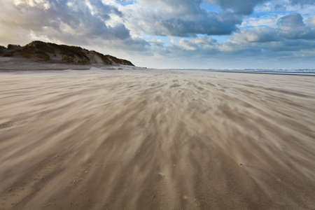 Sand blowing over the beach near the seaの写真素材