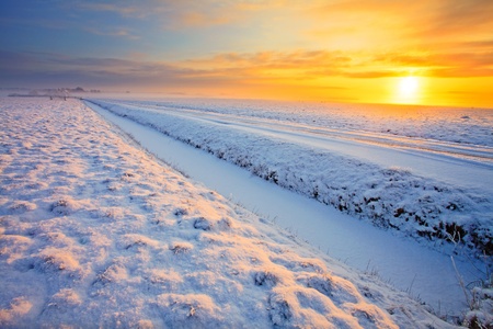 Grassland with ditch in winter at sunsetの写真素材