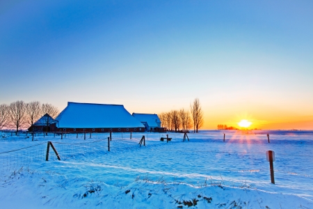 Sunset of farm in white winter landscapeの写真素材