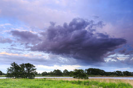 Countryside landscape with a river running through and dark cloudsの写真素材