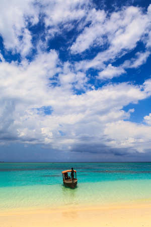 A traditional  boat near a tropical beach with dark cloudsの写真素材