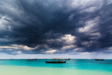 Dark storm clouds above a tropical beach with fishing boats