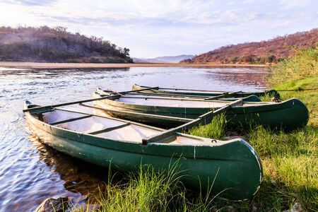 Rowing boat lying on the banks of a river lit by morning sunの写真素材