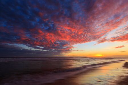 Beautiful colored clouds over the ocean at the beach at sunsetの写真素材
