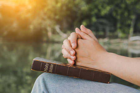 Woman praying on nature background.Hands folded in prayer on a Holy Bible for faith, spirituality and religionの写真素材