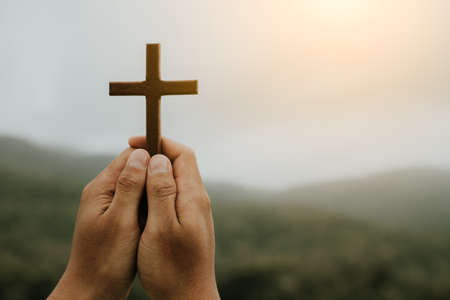 man praying with cross in nature sunrise background, Symbol of Faith.の写真素材