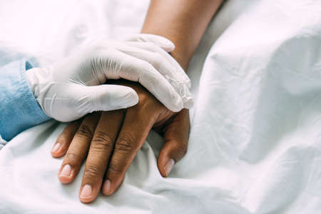 doctor hands holding patient hand for encouragement and empathy. Partnership, trust and medical ethics concept.の写真素材
