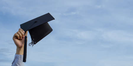Graduation day,Mortar board in hand with sky background, Happiness feeling,Congratulation.の写真素材