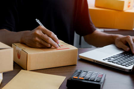 Shipping shopping online ,Online seller writing address on cardboard box at workplace.work at homeの写真素材