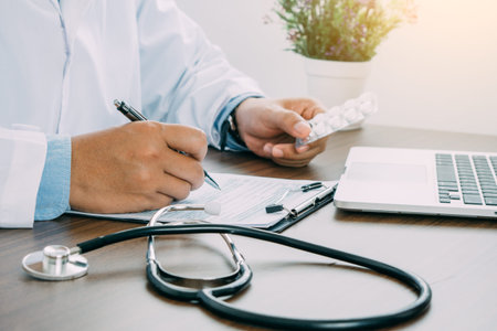 Medicine in doctor hands and heart rate checking report paper's patient diagnosing of doctor on table work.の写真素材