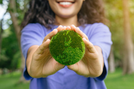 smiling woman holding planet in hands against green spring background. Earth day concept. earth in hands. save of earth.World environment day and sustainable environment concept.の写真素材