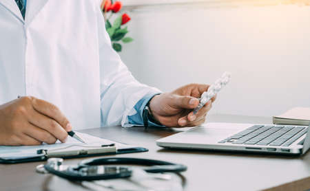 Medicine in doctor hands and heart rate checking report paper's patient diagnosing of doctor on table work.の写真素材