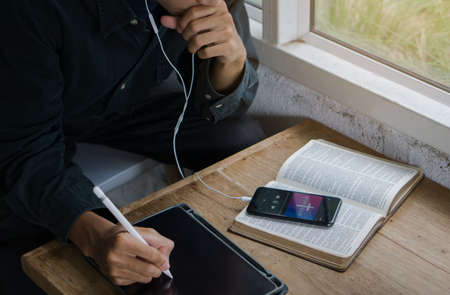 Christian man listen to worship song and praying to GOD with church online Sunday Live Church with the bible.Quarantine from pandemic.の写真素材