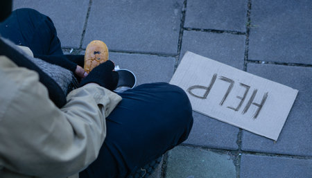 Beggar,Homeless adult man sitting on the street to get help. Indifference of people. Social issues.Help word On Cardboard.の写真素材