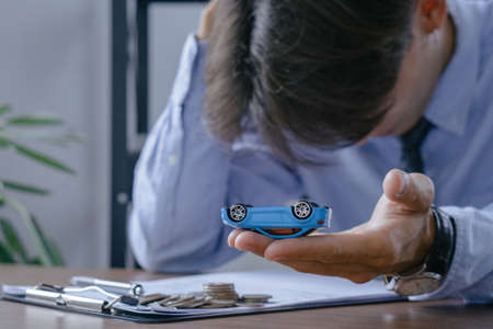 Car insurance concept.Insurance officer stressed while inspecting car damages and filling out claim after accident.の写真素材