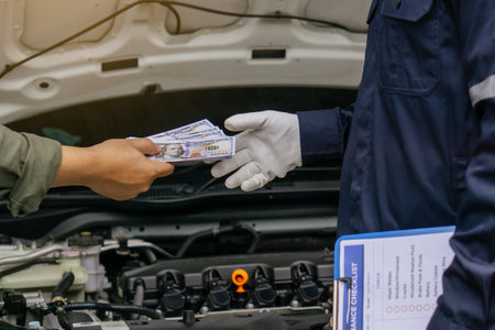 Mechanic man takes cash as payment from customer.after finish checking car system.Professional service.checking the opened hood car.Repair service.の写真素材