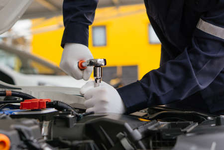 Mechanic man working onsite service on the engine of the car.Car service and maintenance,Repair service.Checks car engine under the hoodの写真素材