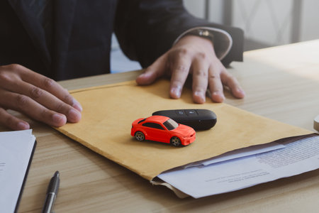 Concept for buying car.The salesman holds documents, car models and car keys for customers after a...