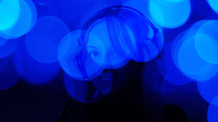 Attractive young woman listening to music blue defocused backgroundの写真素材