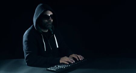 Hacker hacking on laptop keyboard, black backgroundの写真素材