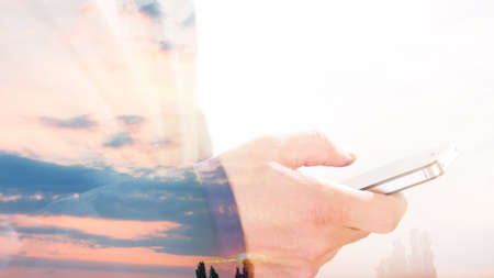 Businessman using smartphone double exposure beautiful sunrise morning skyの写真素材