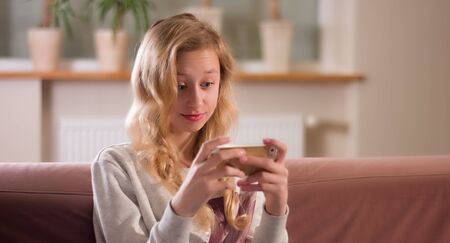Blonde young girl focus on smartphone screenの写真素材