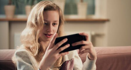 Teenager connected to home internet Wi-Fi playing new smartphone app gameの写真素材