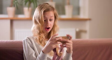 Young girl focus on smartphone screen, online surfing internetの写真素材