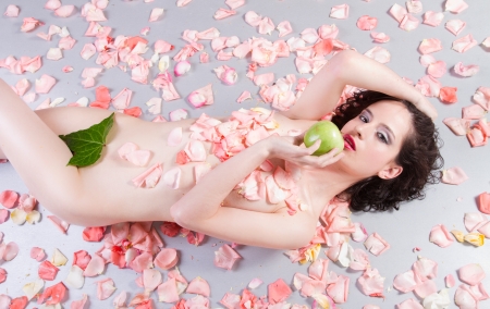 nude woman with roses eating a green appleの写真素材
