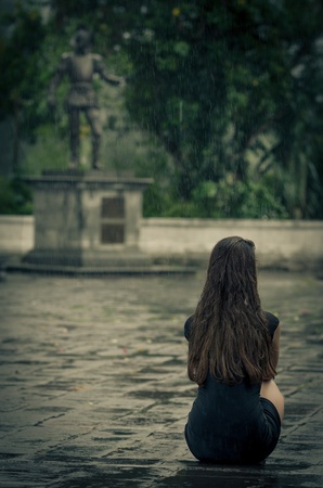 Woman sitting in the rain, with little black dressの写真素材