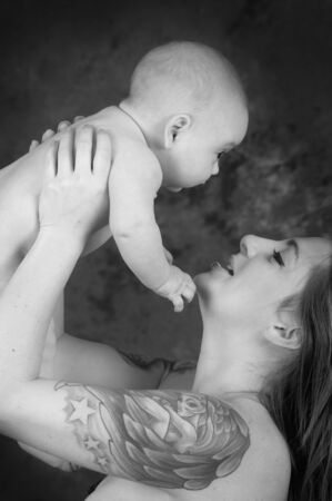 mother with tattoos holding a baby color processedの写真素材