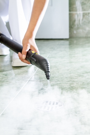 Woman cleaning  drain in bathroom with steamの写真素材